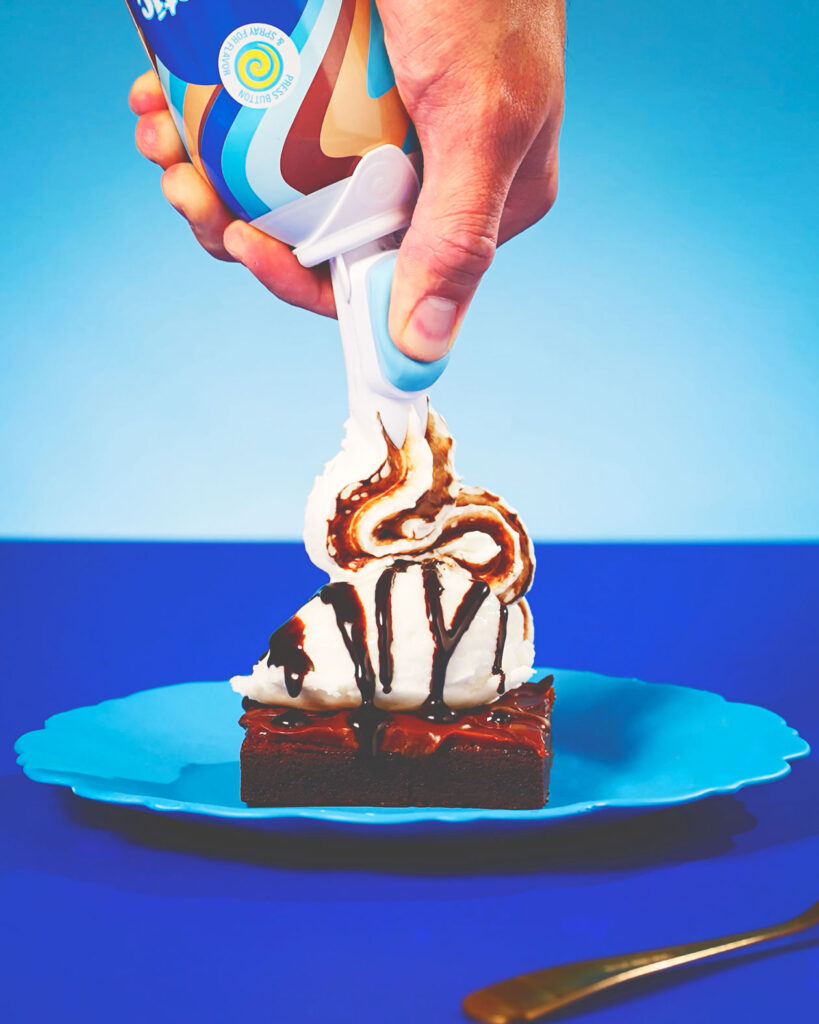 A dollop of Whipnotic flavored whipped cream is put on a brownie with ice cream.