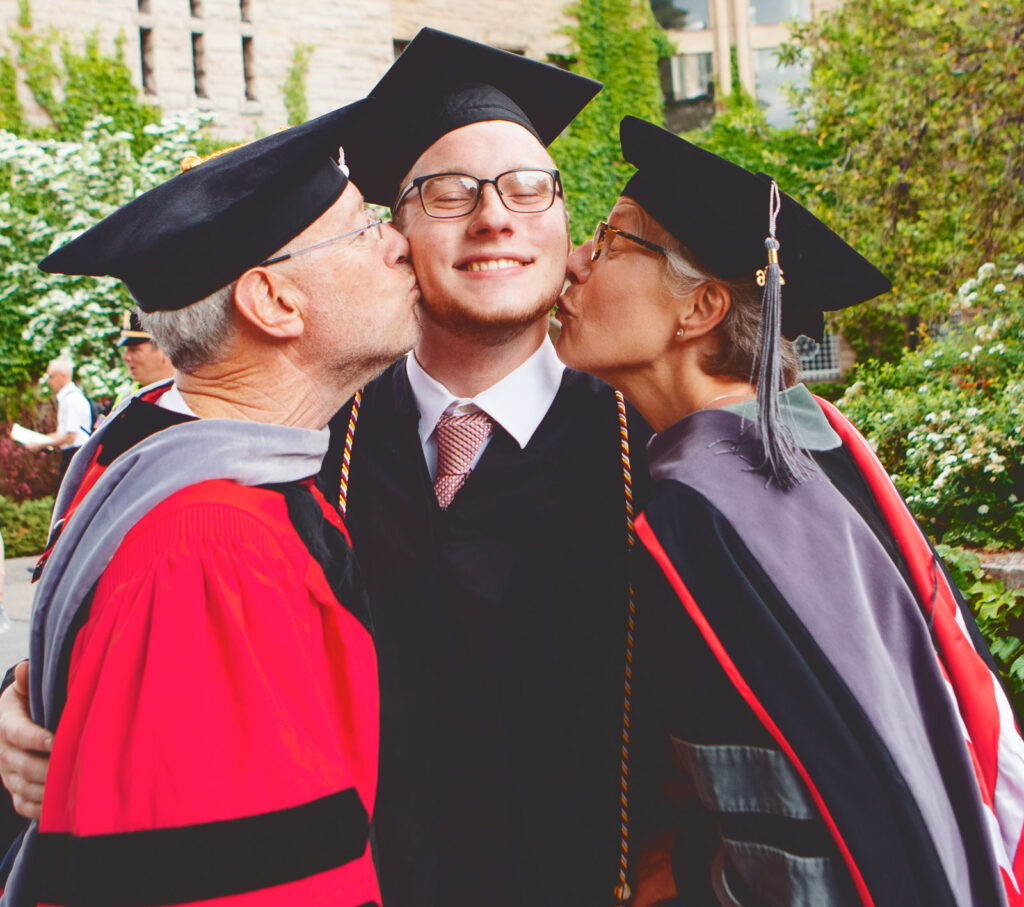 then-Provost Michael Kotlikoff and his wife, professor Carolyn McDaniel, kiss their son, Emmett ’16, during the Commencement procession in 2016