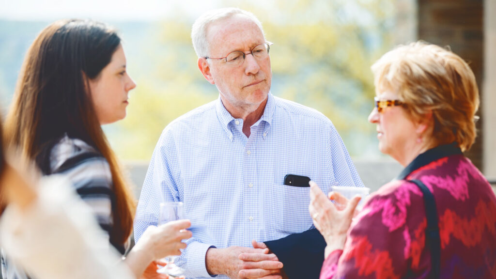 then-Provost Mike Kotlikoff chats with colleagues during a reception for women faculty on the Willard Straight Hall terrace in 2018