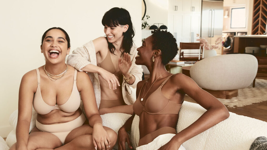 Three models smile together while wearing Harper Wilde bras and underwear.