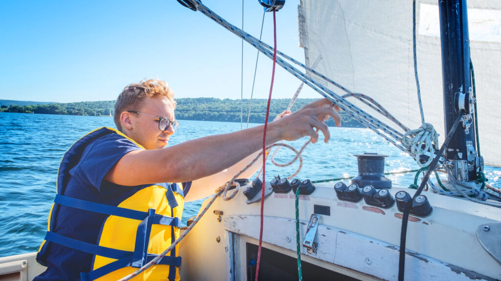 Geoff Miller, a rowing captain for the Big Red, adjusts rigging on a sailboat during the class