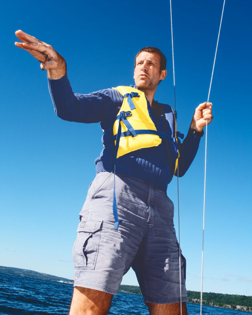 Professor Georg Hoffstaetter de Torquat stands in a sailboat on Cayuga Lake