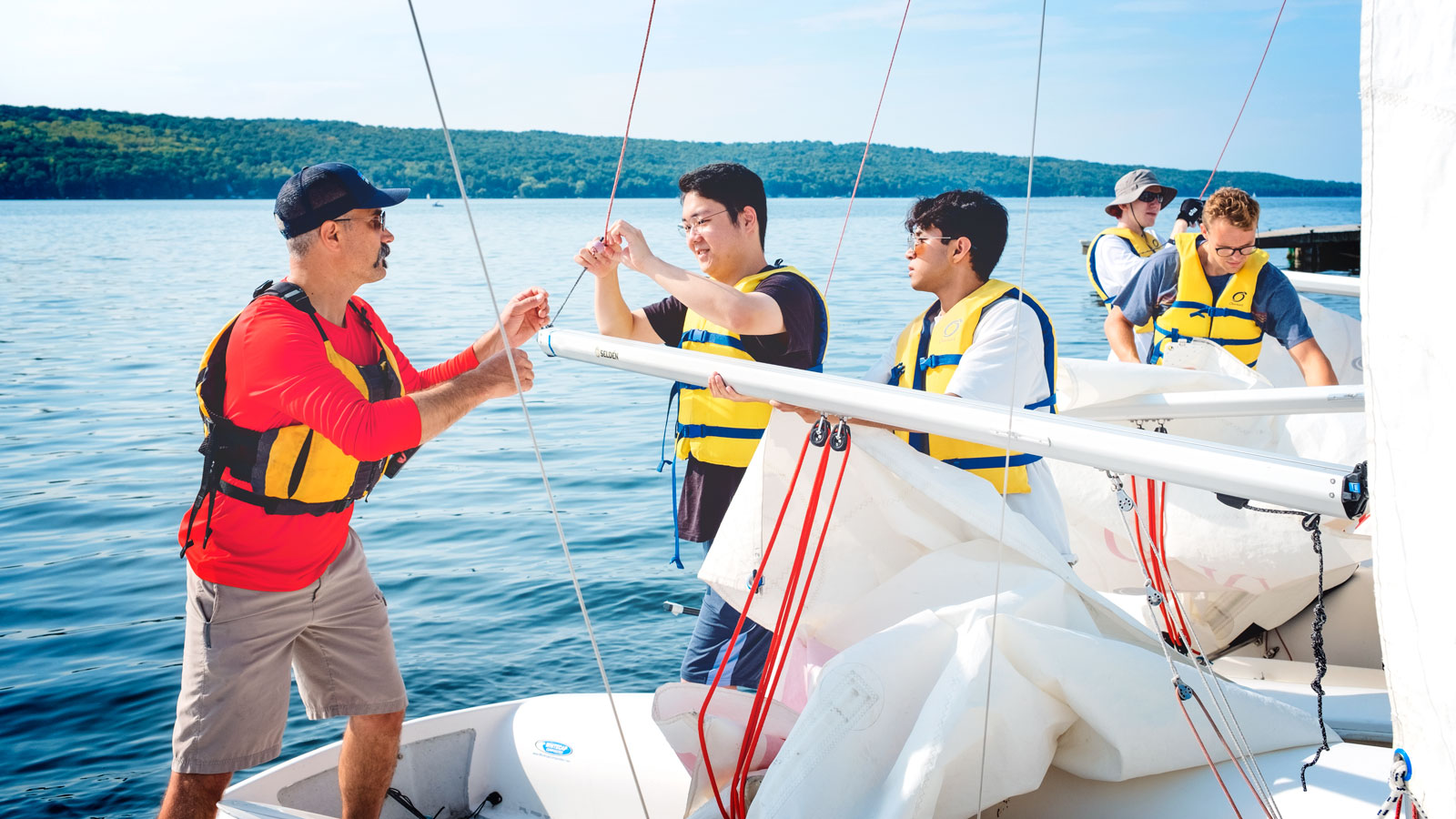 Students in the Physics of Sailing class, along with an experienced sailor from the sailing center, prepare a boat for launch