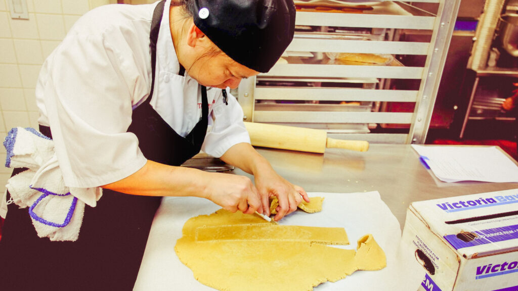 Haidee Bowles, line cook at the Cornell Club-NYC, cuts one of the tower sides for the McGraw gingerbread tower out of the rolled-out batter