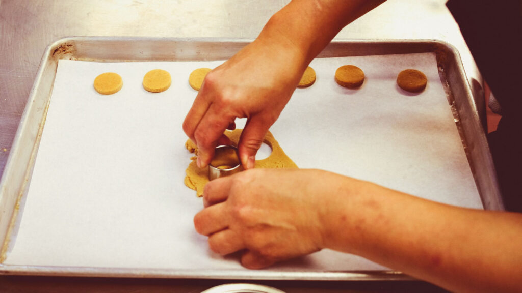 using a one-inch round cookie cutter to make clockface circles out of the gingerbread batter