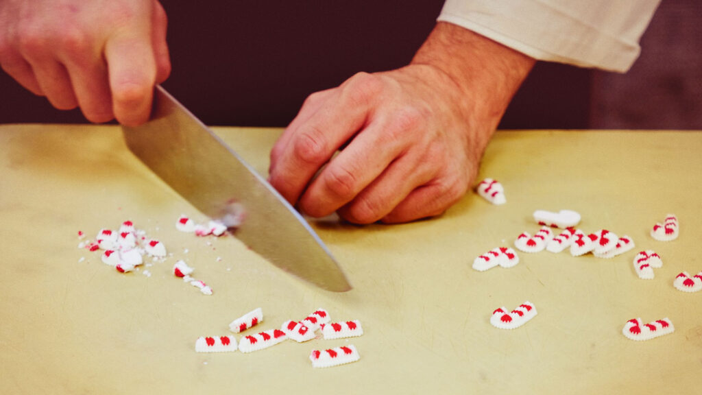 small decorative candy cane pieces are cut smaller for use in adorning the gingerbread McGraw Tower in the Cornell Club-NYC kitchen