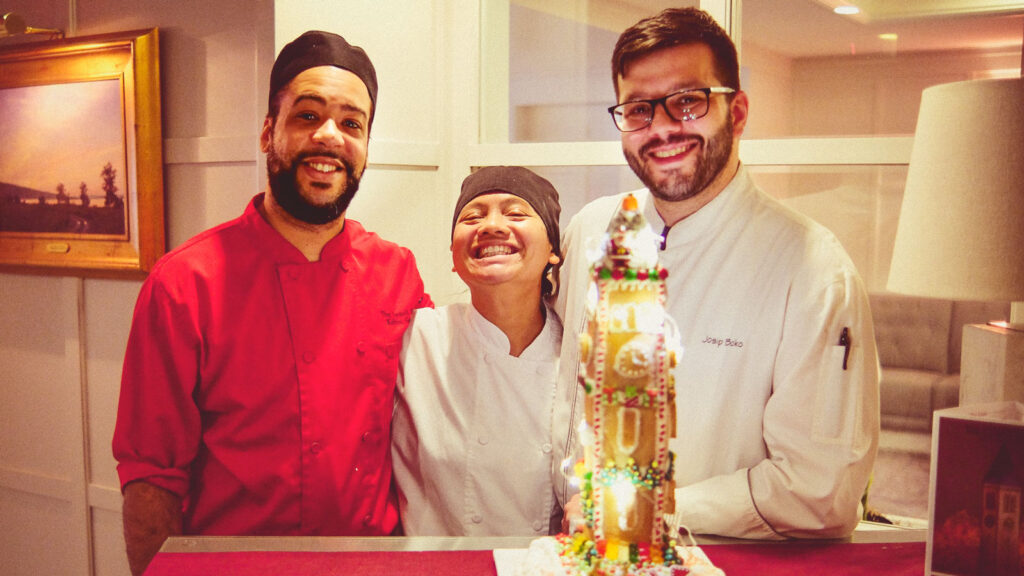 From left, Kelvin Gomez, executive sous chef at the Cornell Club-NYC; Haidee Bowles, line cook; and Joe Boko, executive chef, pose with the completed gingerbread McGraw Tower