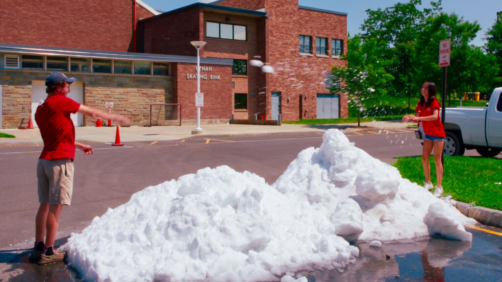 Two visitors to campus in July 2013 have an impromptu snowball fight using the Lynah ice shavings in its parking lot