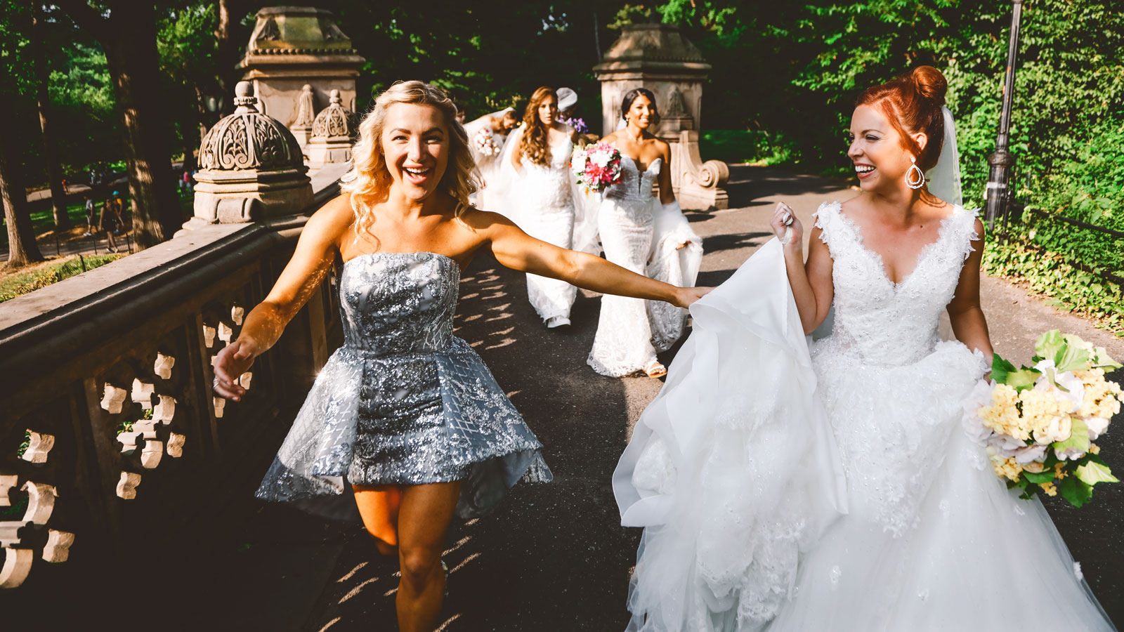 Hayley Paige Gutman smiling and walking with models wearing her wedding dresses and carrying flowers.