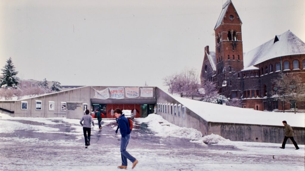 students walk past the Cornell Store exterior on Ho Plaza in snow and slush in 1984