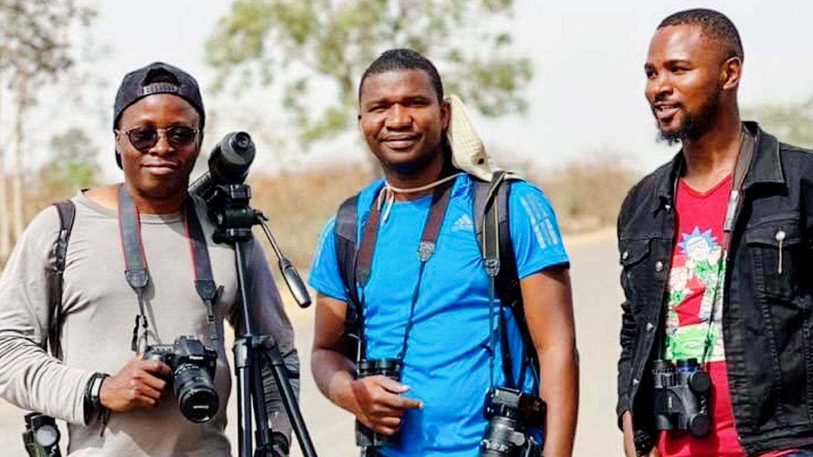 Three men in Nigeria birdwatching with cameras and binoculars.