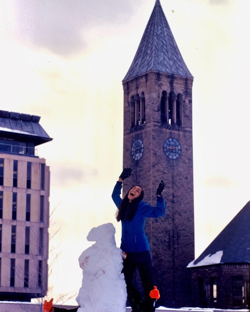 a student poses with a snow sculpture with McGraw Tower in the background in 1967