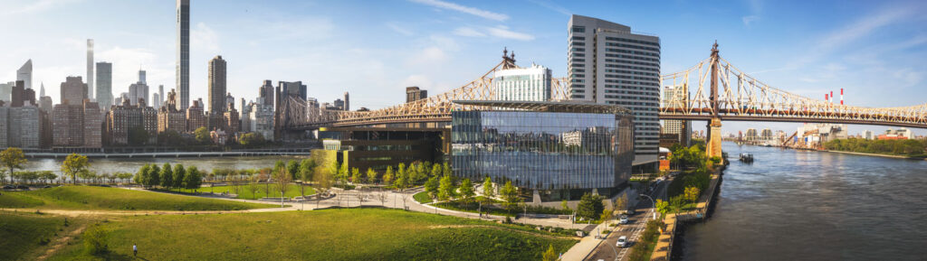 wide panoramic view facing north of the Cornell Tech campus with the Manhattan skyline and the Queensboro Bridge in the background