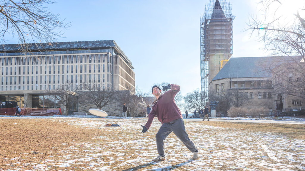 Students play frisbee in the winter on the Arts Quad