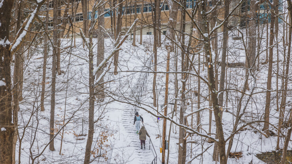 Students walking on the Cascadilla Gorge trail towards Rhodes Hall during a snowstorm