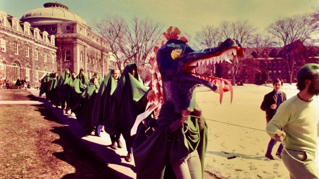 A mostly human dragon passes by Sibley Hall on what was Green Dragon Day 1970