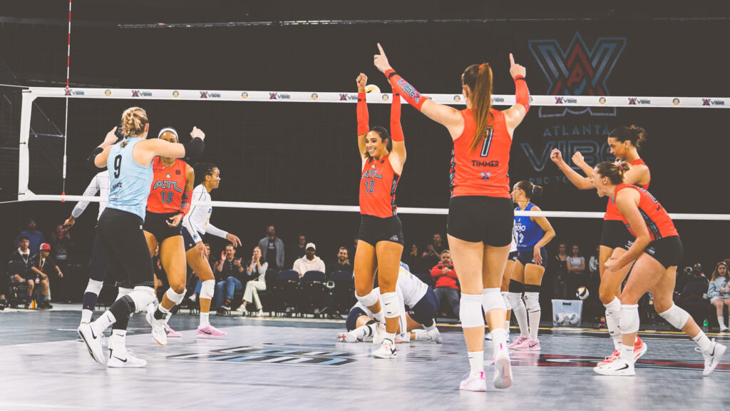 The Atlanta Vibe team celebrates on the court after winning a point during a match in the Gas South Arena.