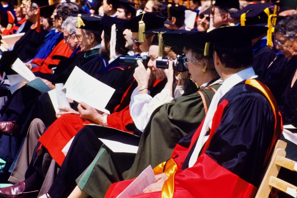 A row of robed faculty, some taking photos