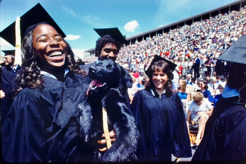 A grad holds a dog at Commencement.