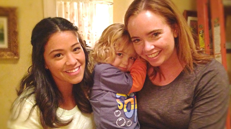 Jessica O'Toole holds her young son Gus and smiles next to Gina Rodriguez from Jane the Virgin.