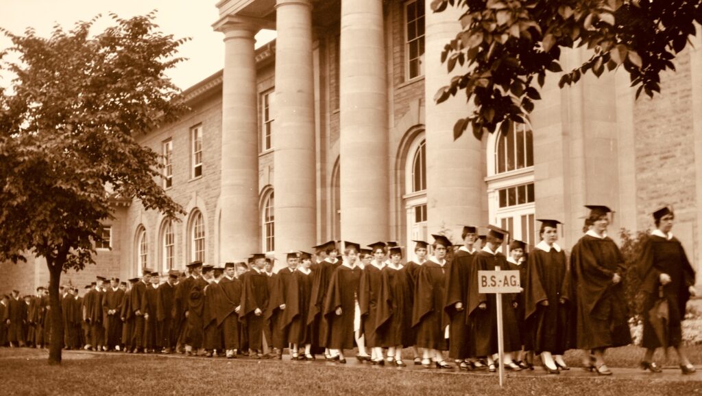 Graduates in caps and gowns process past Goldwin Smith Hall in 1917