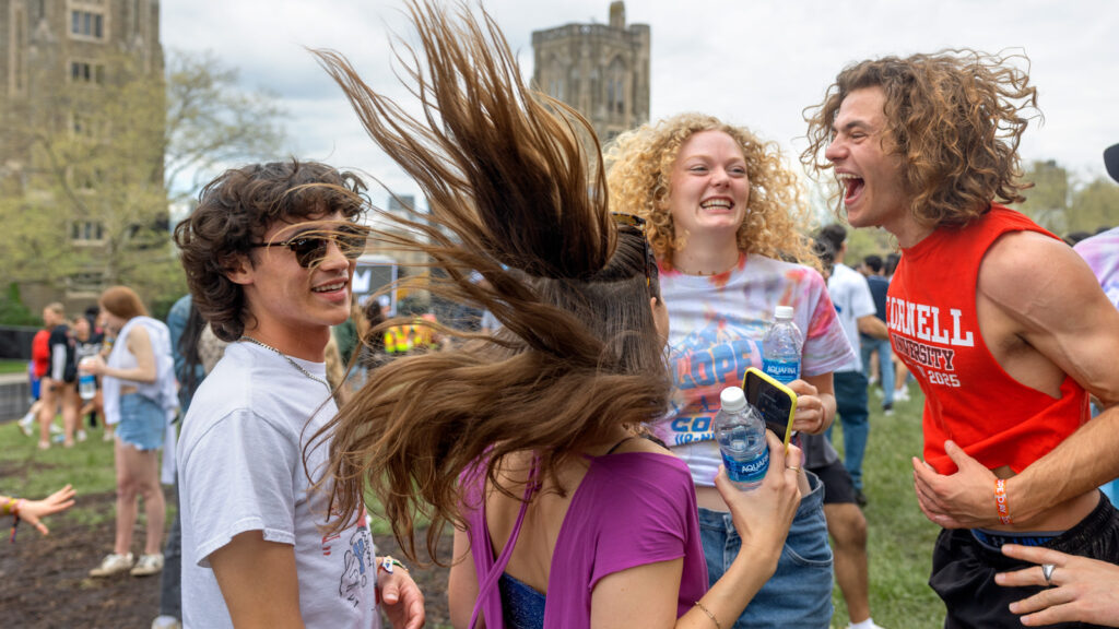 Four students smiling, yelling, and dancing together.