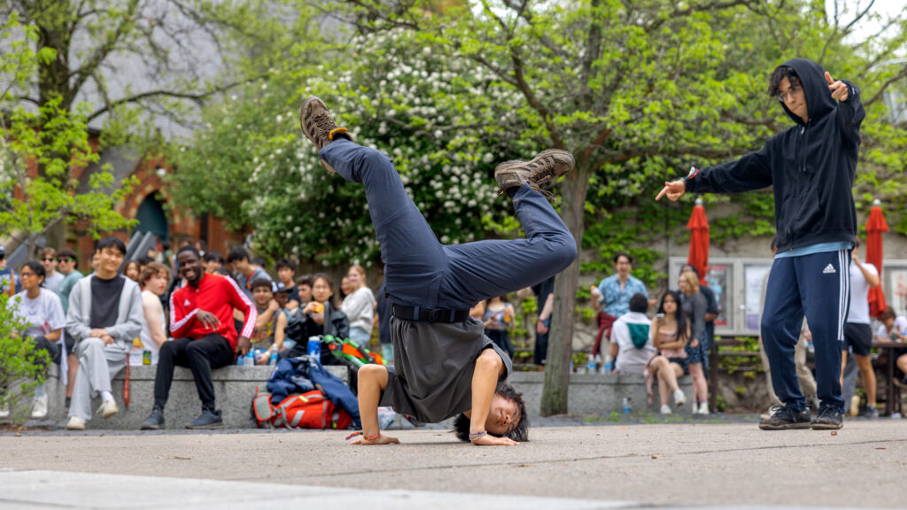 A person breakdances while a crowd of people watch in the background.