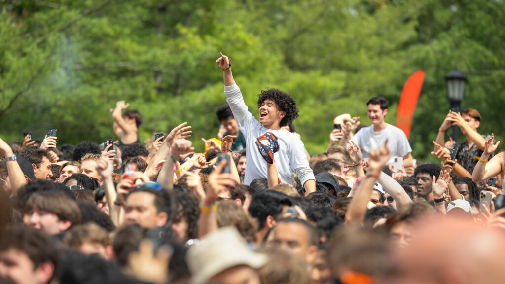The crowd at Slope Day with a few people above the crowd being held up by others.