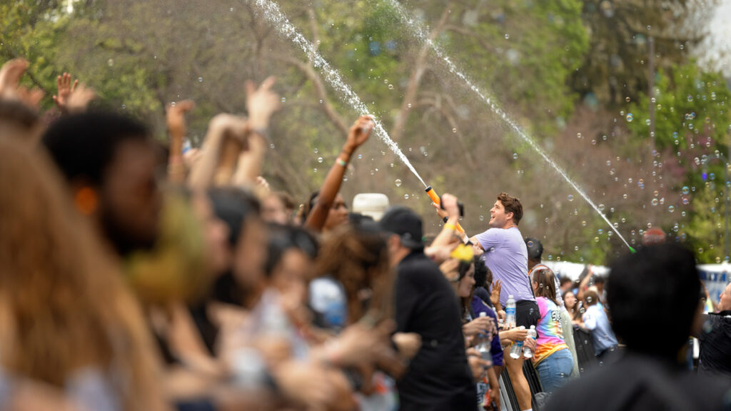 People with water squirters send streams of water flying into the crowd.