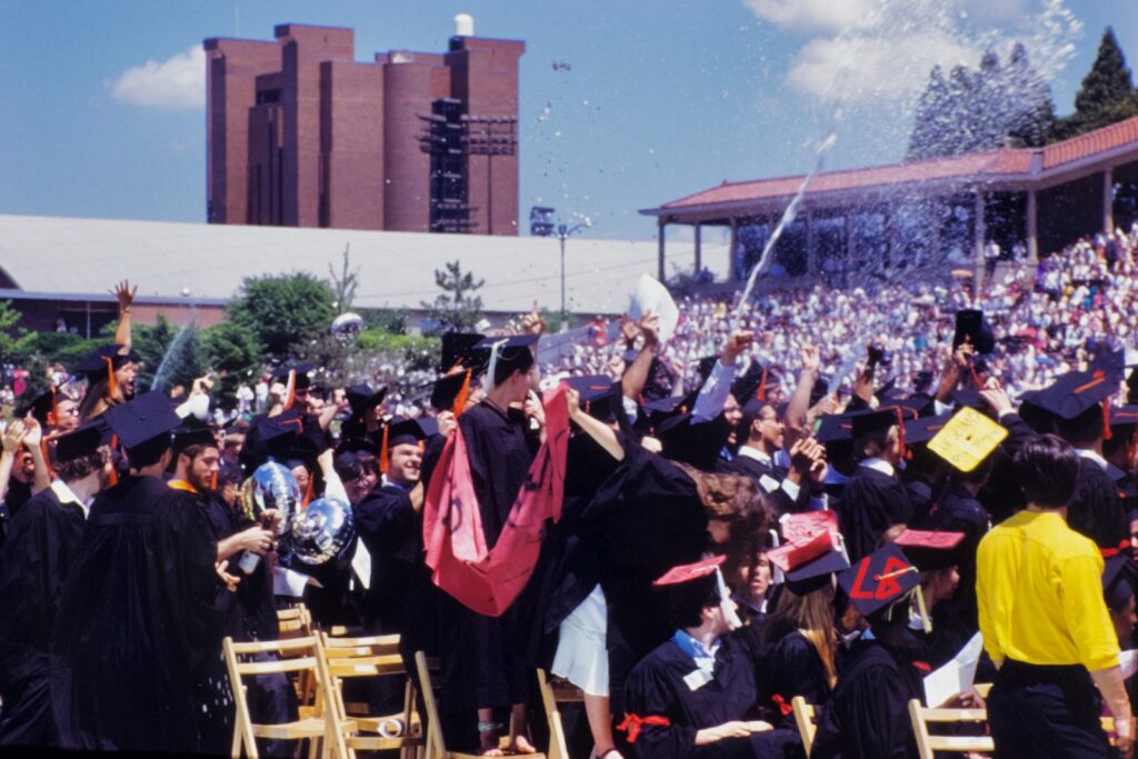 A bottle of champagne explodes on the field at Commencement 1985