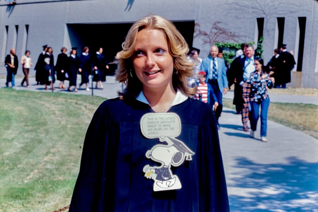 a graduating senior in 1977 wears a Snoopy emblem stating "This is the world famous graduate about to make his mark on the world!"