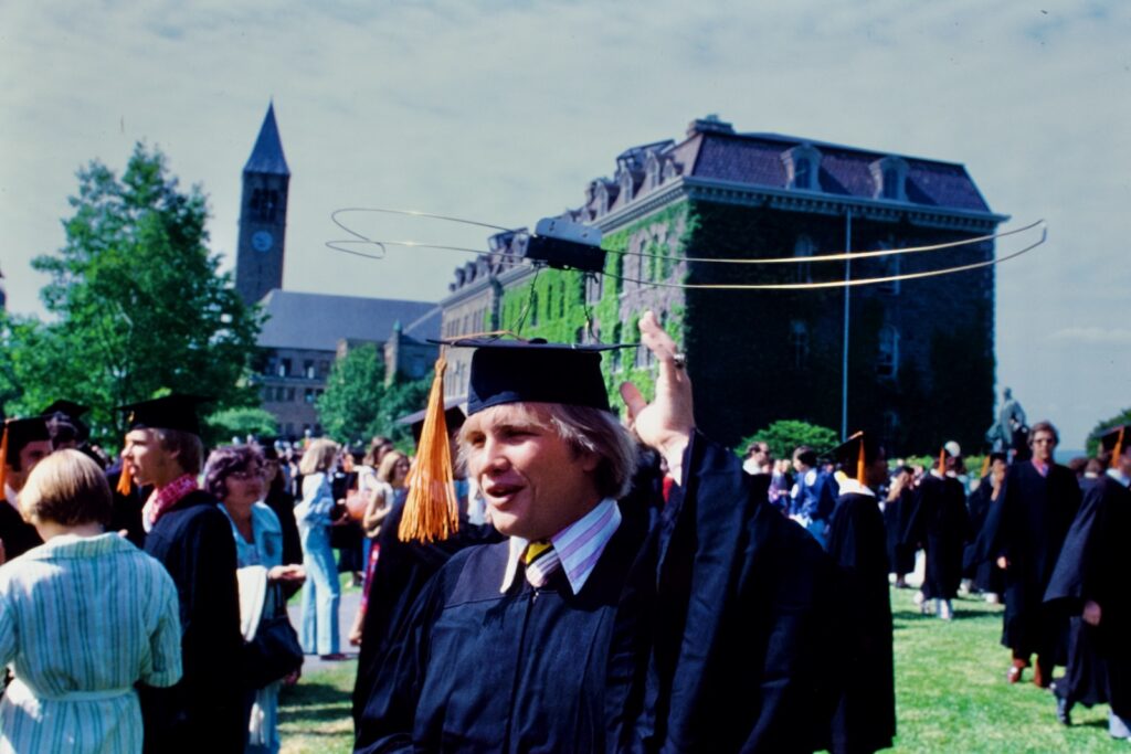 a graduating student on the Arts Quad wears a wire antenna of some sort on his mortarboard in 1977
