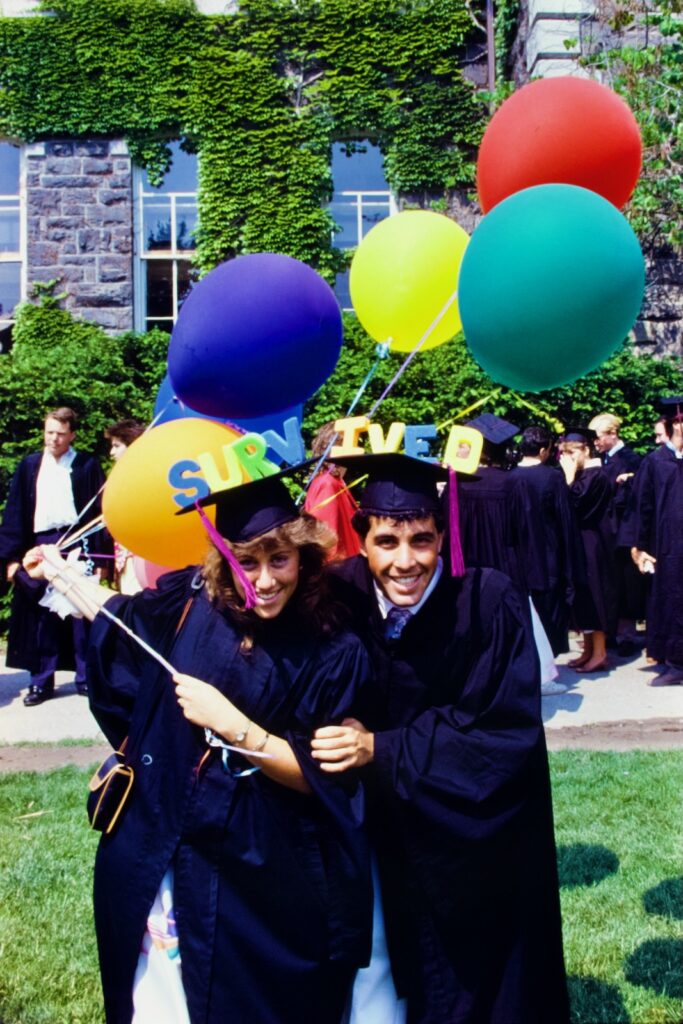 graduating seniors in 1986 sport letters spelling "survived" across their two mortarboards while holding balloons