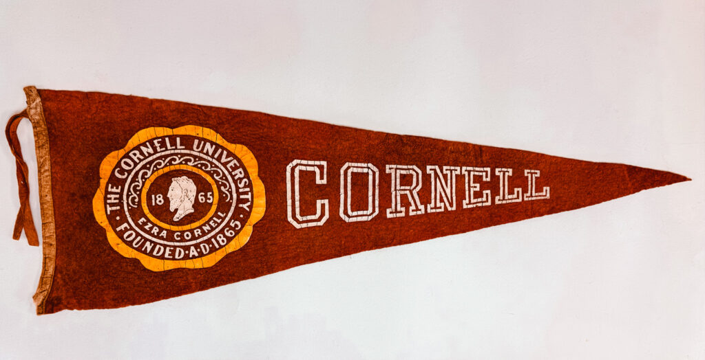 a Cornell pennant with a stylized version of the Great Seal at its center, including the text "The Cornell University"