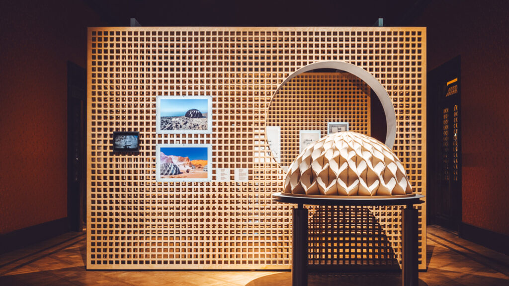 "Beyti Beytak. My Home is Your Home. La mia casa è la tua casa" depicts a wooden wall panel with a circular window, behind a dome appearing to be made of folded paper