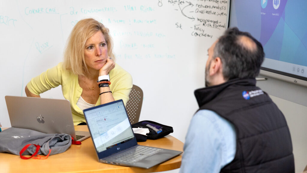 Sarah Kreps, director of the Tech Policy Institute in the Cornell Jeb E. Brooks School of Public Policy, sits at a table with a colleague. Each has an open laptop