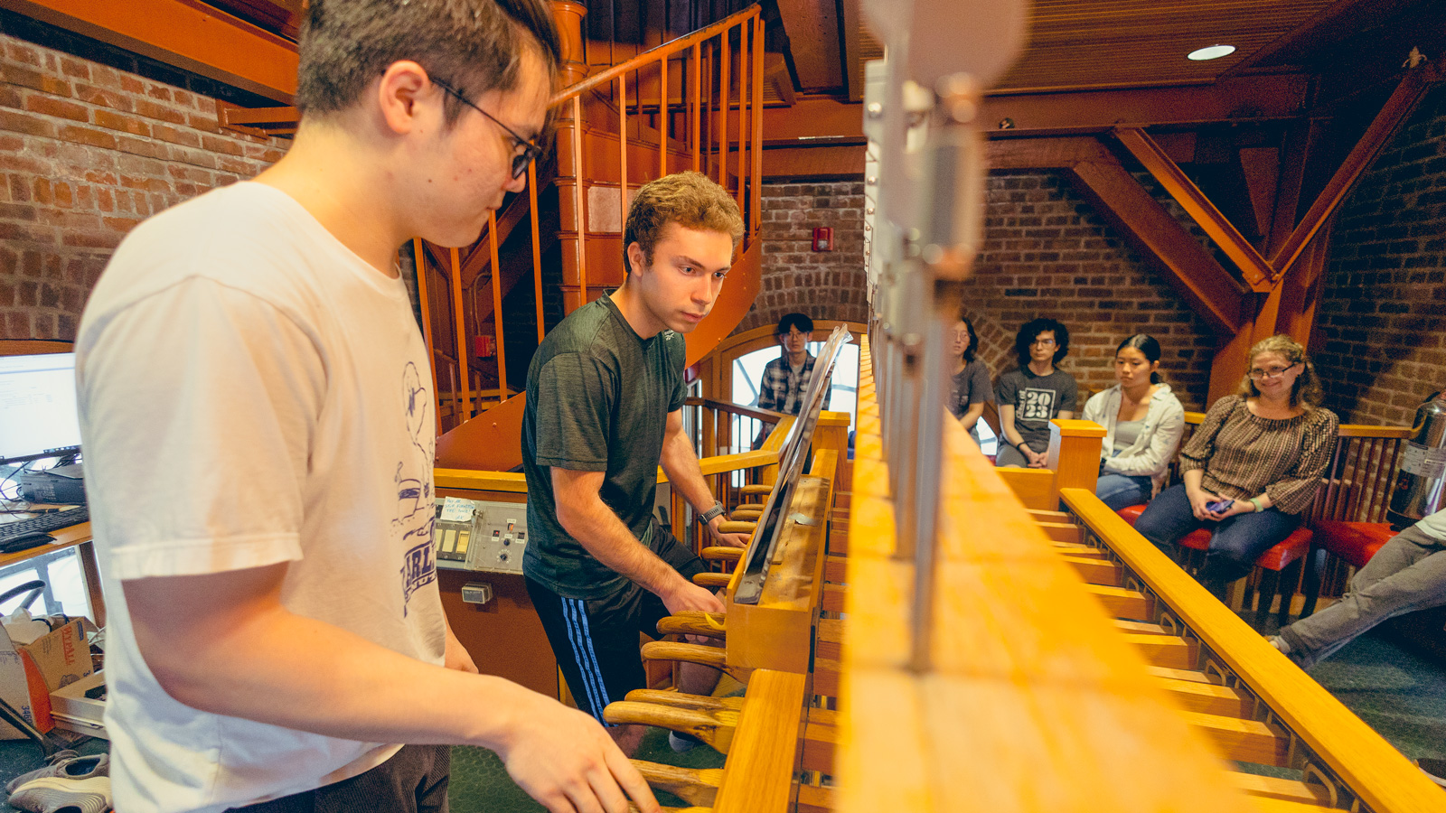 New chimesmaster Andrew Arena and another chimesmaster perform a duet on the chimes in McGraw Tower while other chimesmasters watch them.