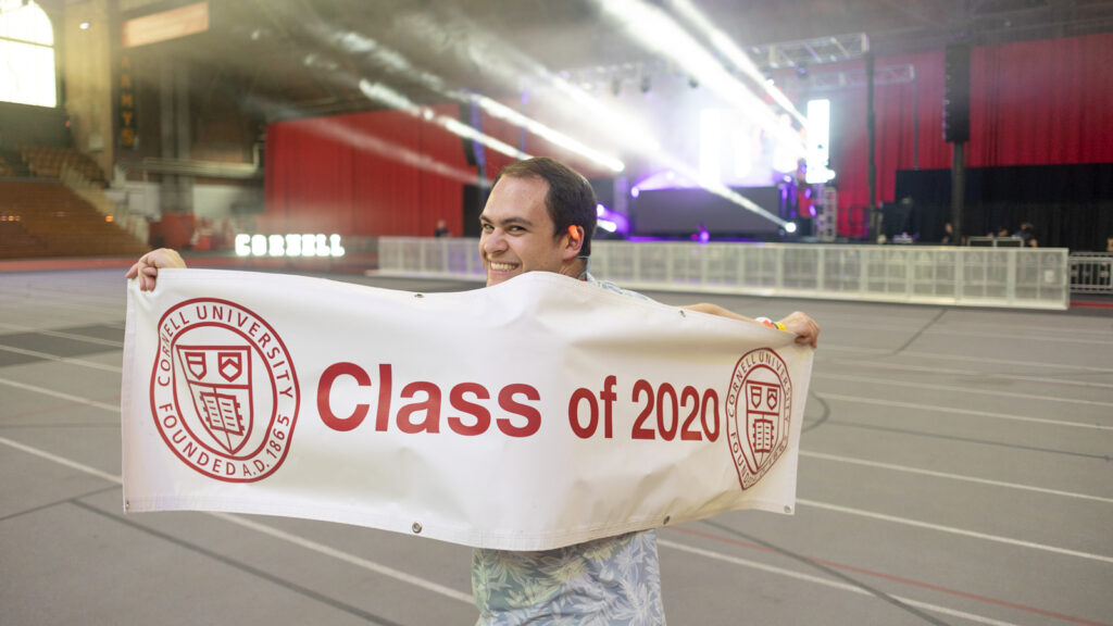 A man holds a "Class of 2020" banner in Barton Hall