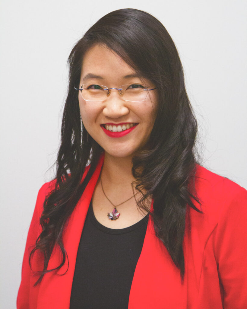 A headshot of Angela Lu smiling wearing a red blazer and black shirt.