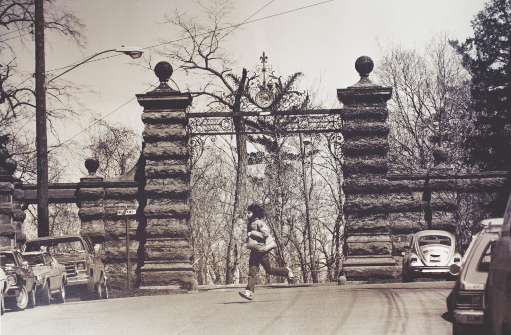 A student runs across Eddy Street with Eddy Gate visible in the background, 1970s