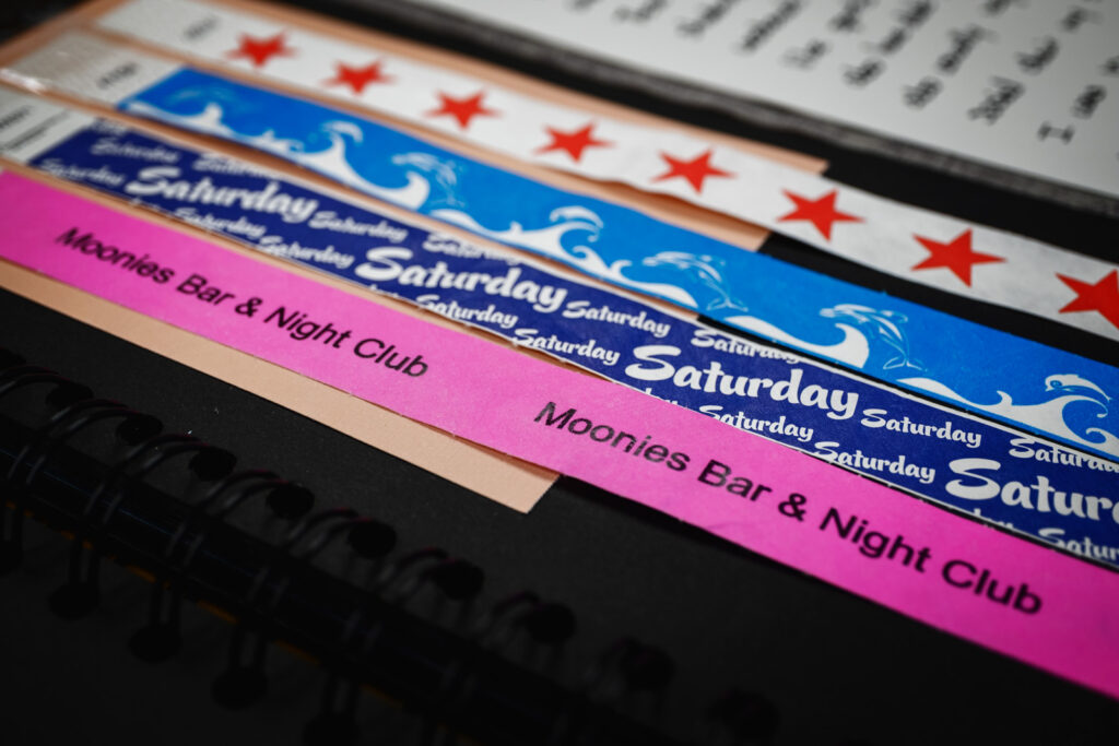 page of a student's scrapbook made for final project for AMST 2001 course showing wristbands from several local nightclubs and events