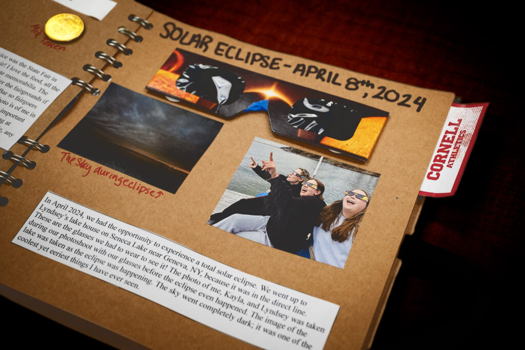 page of a student's scrapbook made for final project for AMST 2001 course showing the experience of viewing the April 8, 2024 solar eclipse, including two photos, a written paragraph, and the solar eclipse glasses themselves