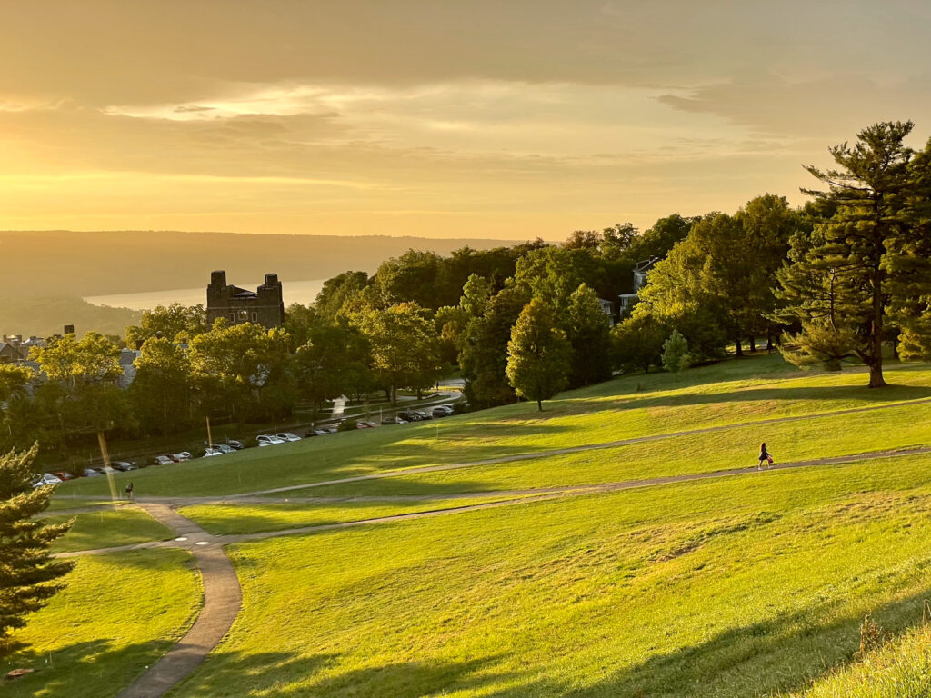 view of the Slope and the trees around it, with part of West Campus and Cayuga Lake in the background