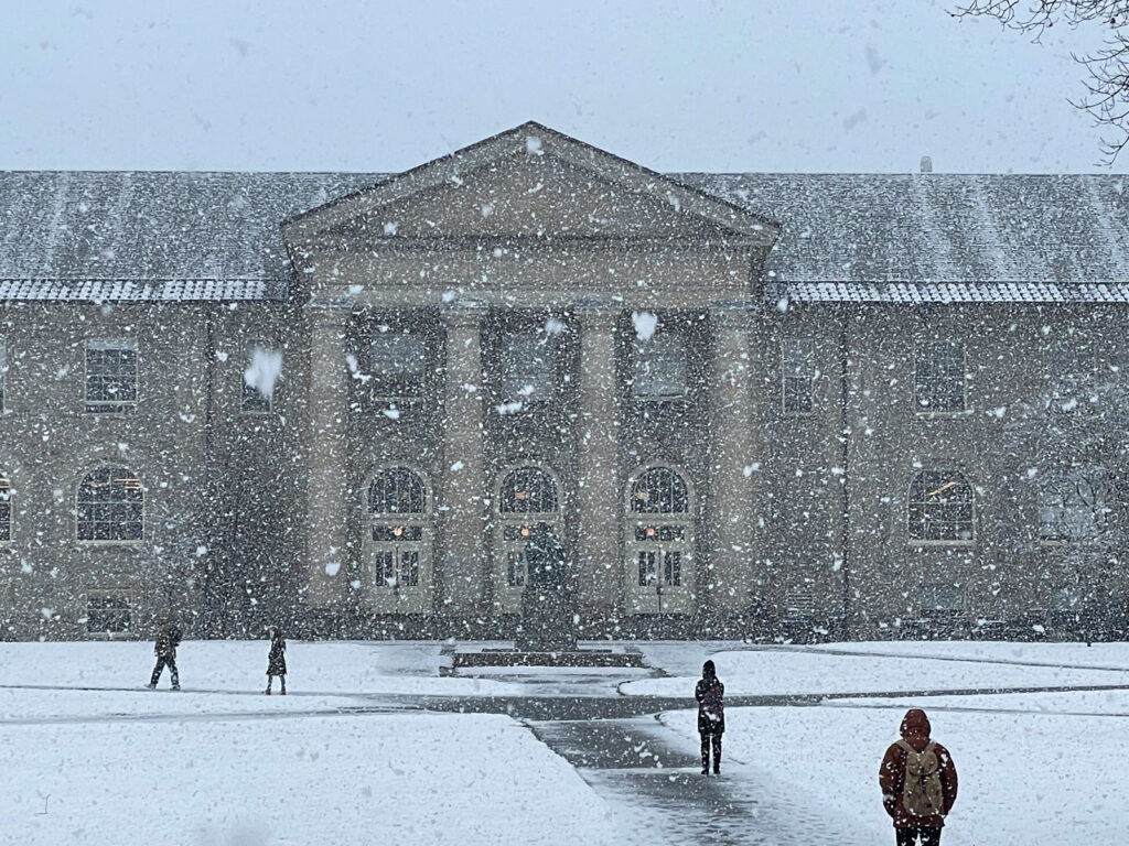 People walk outside Goldwin Smith Hall during a heavy snowfall