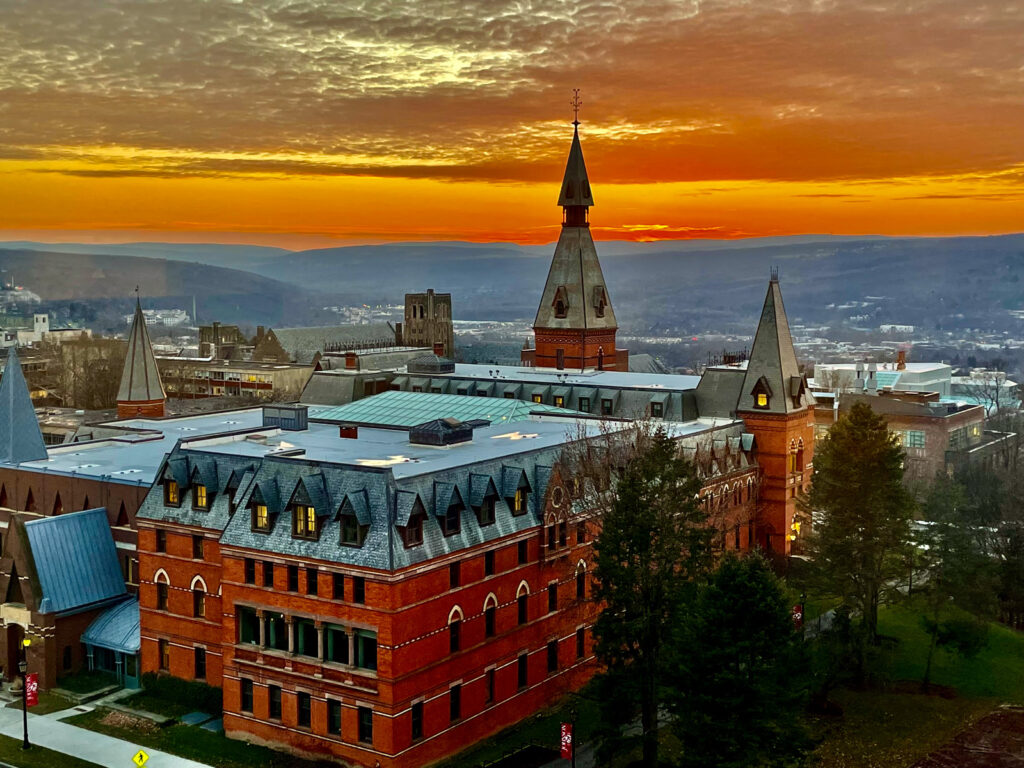 high view of Sage Hall and West Campus and beyond during an orange-hued sunset