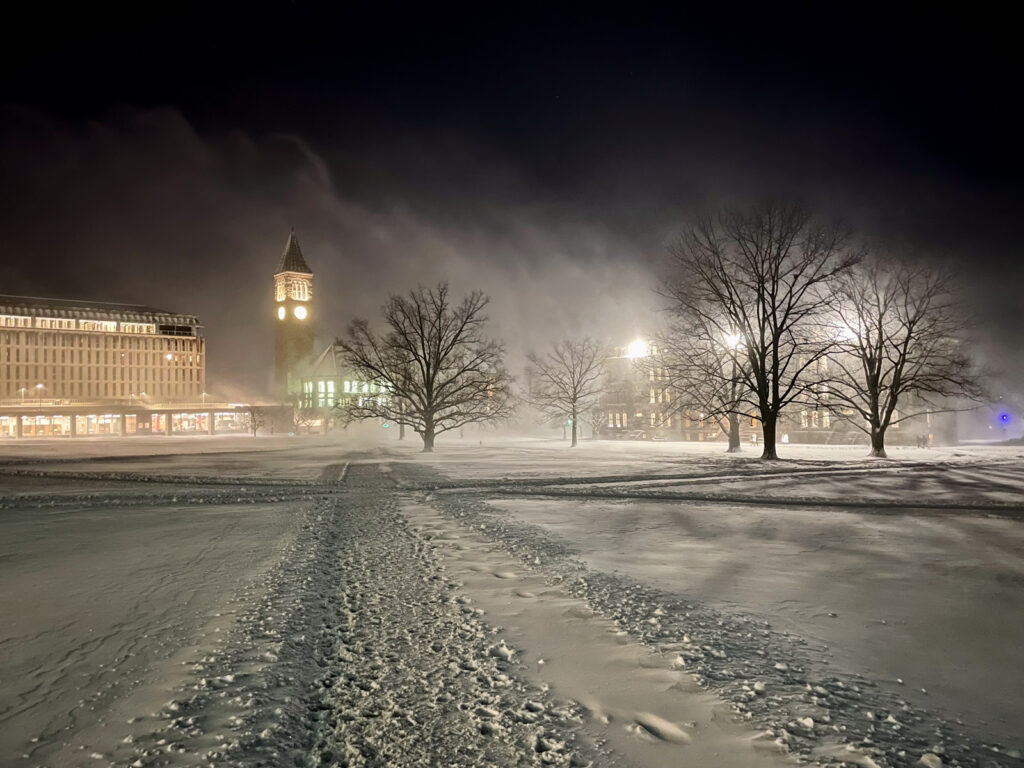 A snowy, winter night on the Arts Quad with the lights from Olin Library, McGraw Tower, and Morrill Hall visible against the dark sky