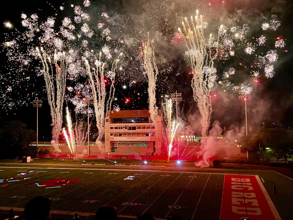 Spectators watch a Homecoming fireworks show at Schoellkopf Field with silver and gold fireworks lighting up the dark sky