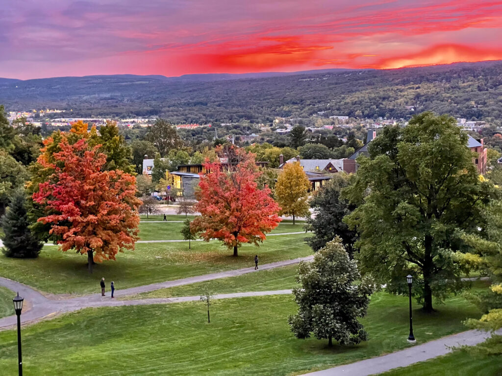 The Slope and a portion of West Campus viewed during a sunset with a pink and purple sky and two red trees visible