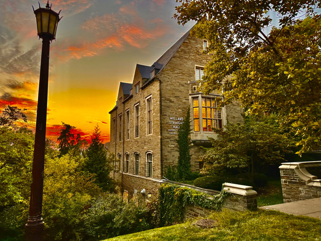 Willard Straight Hall with a blue, yellow, and red sky in the background