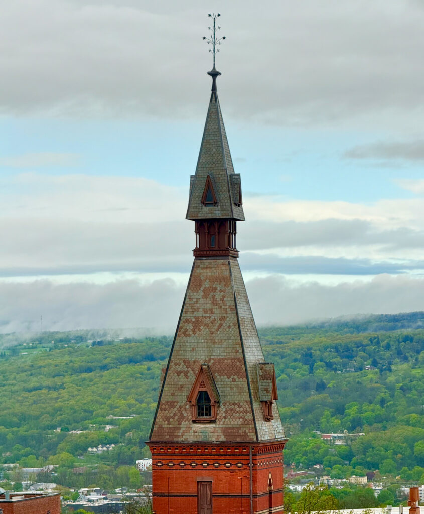 The top of Sage Hall's spire with the hills of the Ithaca area behind